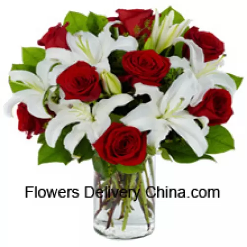 Roses rouges et lys blancs avec des remplissages saisonniers dans un vase en verre