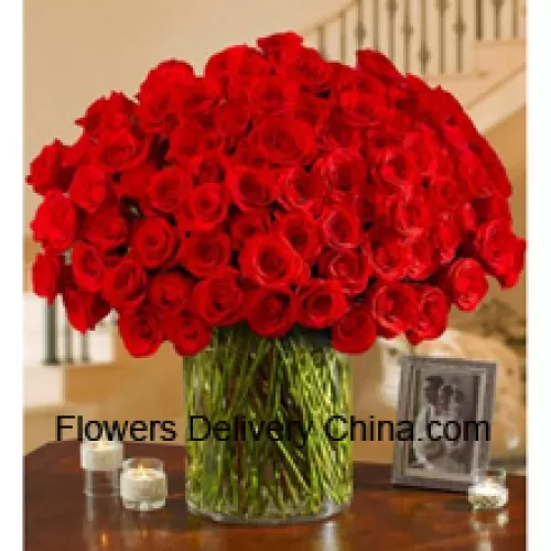 100 rote Rosen mit etwas Farn in einer großen Glasvase