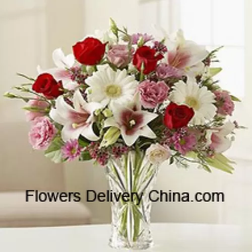 Rosas rojas, claveles rosados, gerberas blancas y lirios blancos con otras flores variadas en un jarrón de vidrio