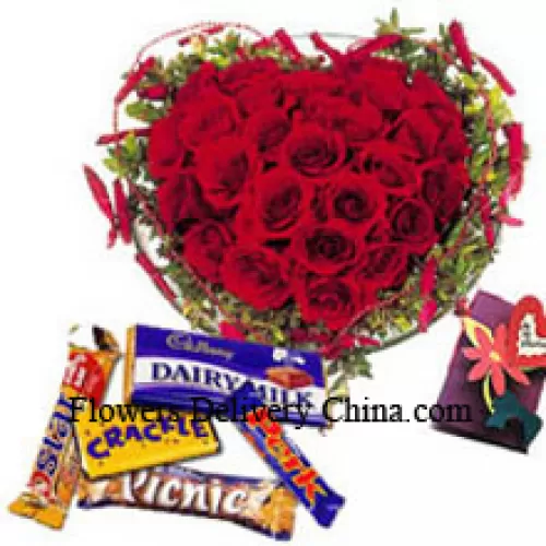 Composizione a forma di cuore di 40 rose rosse, cioccolatini assortiti e una cartolina omaggio
